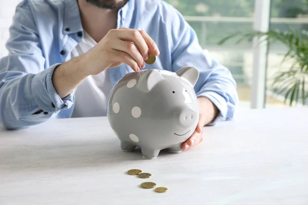 Hombre Poniendo Moneda Alcancía Mesa Blanca Interior Primer Plano — Foto de Stock