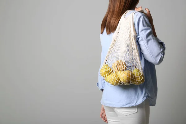 グレーの背景に新鮮な熟した梨と女性がネットバッグを保持 クローズアップ テキストのスペース — ストック写真