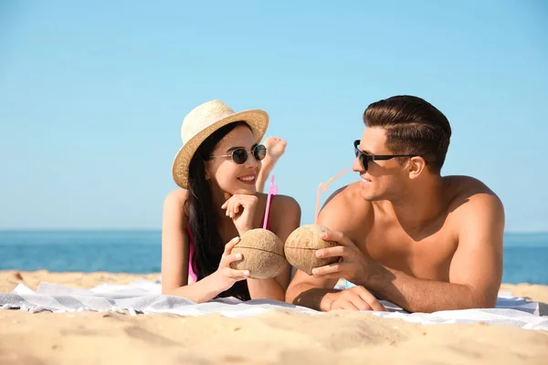 一对快乐的夫妇在度假胜地的阳光海滩上喝着鸡尾酒 — 图库照片