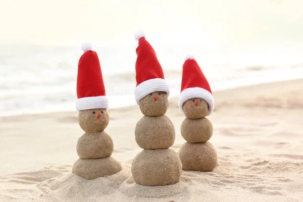 Bałwanów Piasku Czapkami Mikołaja Plaży Pobliżu Morza Święta Bożego Narodzenia — Zdjęcie stockowe