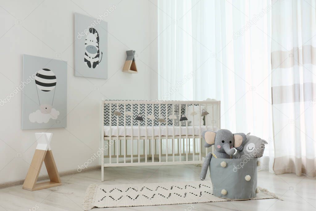 Stylish baby room interior with crib and cute pictures on wall