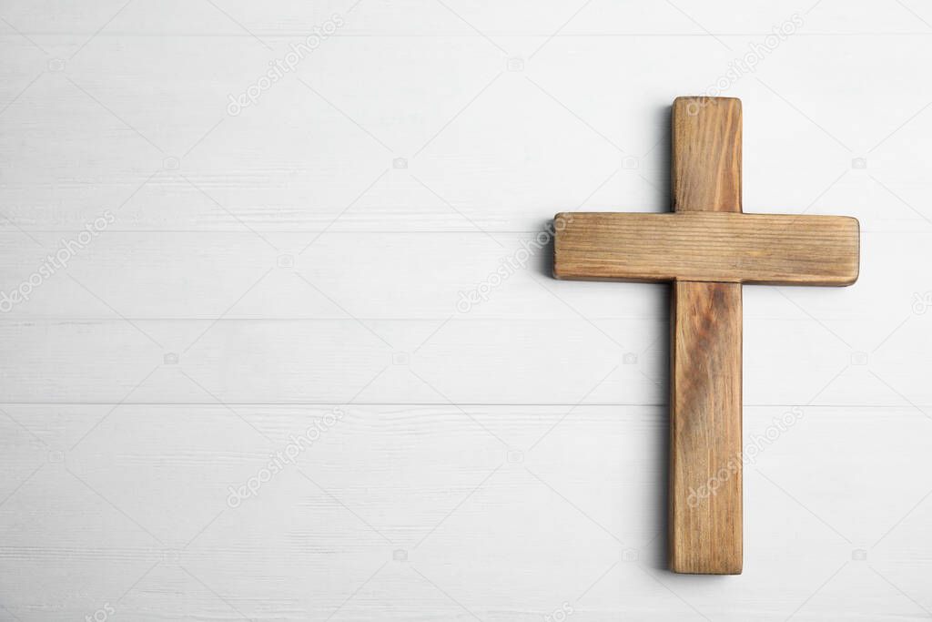 Christian cross on white wooden background, top view with space for text. Religion concept