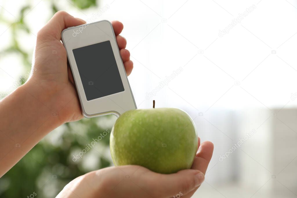 Woman checking apple with nitrate tester at home, closeup