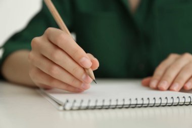 Beyaz masadaki kalemle çizen kadın, yakın plan.