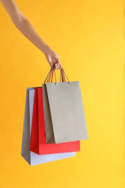 Sarı arka planda kağıt alışveriş torbaları olan kadın, yakın plan.