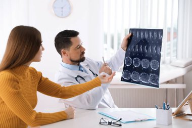 Ortopedist, klinikteki hastaya röntgen filmi gösteriyor.