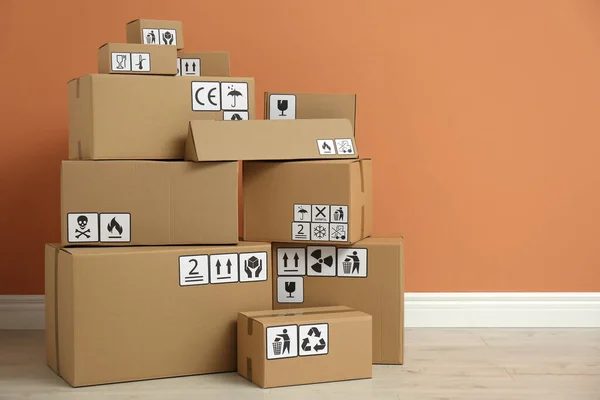 Cajas Cartón Con Diferentes Símbolos Embalaje Suelo Cerca Pared Naranja — Foto de Stock