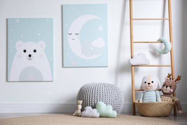 Bebek odasının içinde oyuncaklar ve duvarda sevimli posterler var.