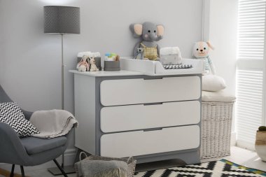 Güzel bir bebek odası. İçinde modern bir masa ve sallanan bir sandalye var.