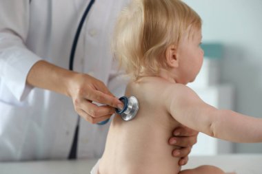 Pediyatrist hastanede steteskopla bebeği muayene ediyor. Sağlık hizmetleri