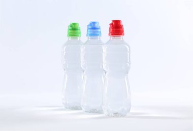 Beyaz zemin üzerinde saf su bulunan plastik şişeler.