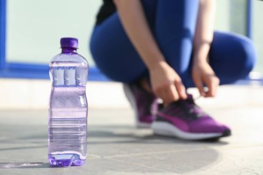 Plastik şişe saf su ve atletik kadın, yakın plan.