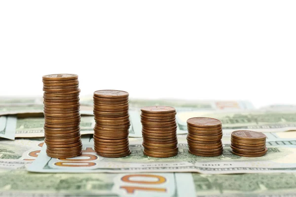 Stacks of metal coins on dollar banknotes against white background