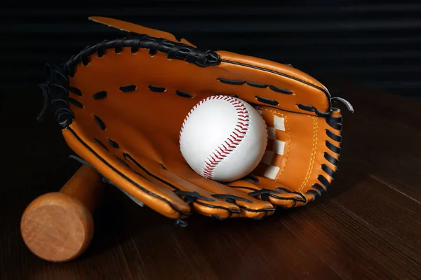 Leather baseball ball, bat and glove on wooden table