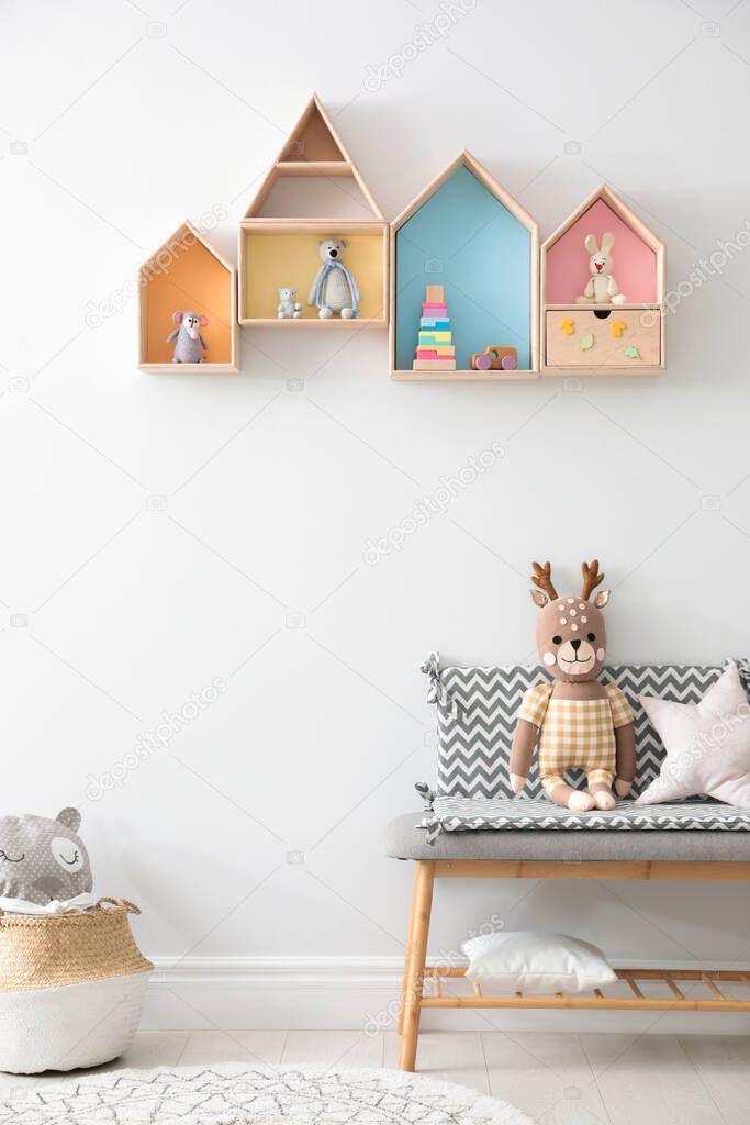 House shaped shelves and bench with toys in children's room. Interior design