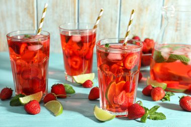 Açık mavi ahşap masada çilekli ve limonlu içecek.