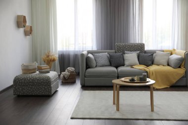 Pencerelerin yanında rahat kanepesi olan şık bir oturma odası. İç tasarım