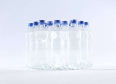 Beyaz zemin üzerinde saf su bulunan plastik şişeler.