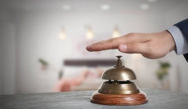 Bulanık arkaplanda otelin servis zilini çalan adam, yakın plan.