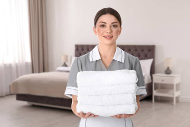 Otel odasında yatağın yanında katlanmış temiz havluları olan güzel oda hizmetçisi.