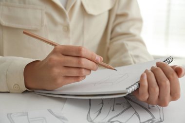 Beyaz masadaki kalemle çizen kadın, yakın plan.