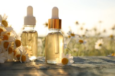 Arazideki mavi ahşap masada gerekli yağ ve papatya çayları. Metin için boşluk