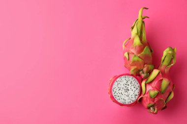 Lezzetli kesim ve tüm ejderha meyveleri (pitahaya) pembe arka planda, düz yatıyordu. Metin için boşluk