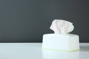 Beyaz masanın üzerinde kağıt mendil olan tutucu. Metin için boşluk