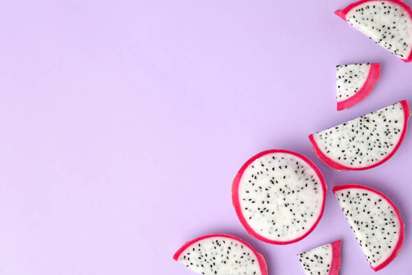 Slices of delicious dragon fruit (pitahaya) on violet background, flat lay. Space for text