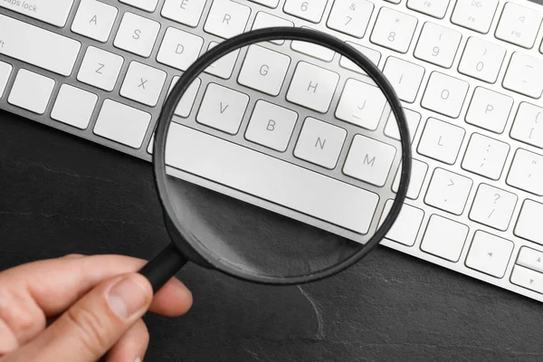 Woman Holding Magnifier Glass Keyboard Black Slate Table Top View — Stock Photo, Image