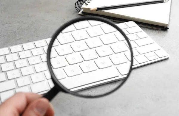 Mujer Sosteniendo Lupa Cerca Del Teclado Mesa Piedra Gris Claro — Foto de Stock