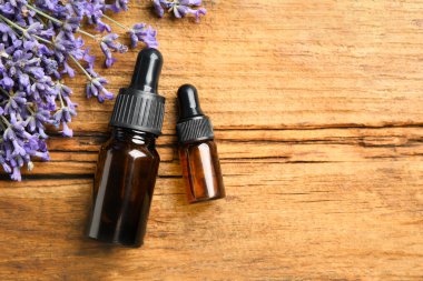 Düz kompozisyon, lavanta çiçekleri ve ahşap arka planda gerekli yağ. Metin için boşluk