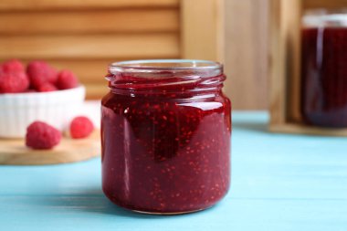 Açık mavi ahşap masada nefis ahududu reçeli, yakın plan.