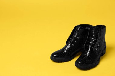 Sarı arka planda bir çift şık ayak bileği çizmesi. Metin için boşluk