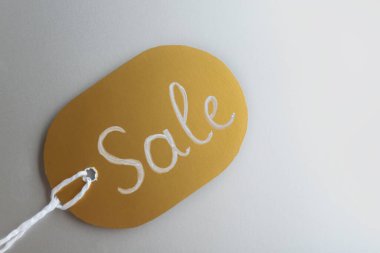 Açık gri arka planda kelime satışı ile altın etiket, üst görünüm. Kara Cuma konsepti