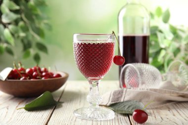 Lezzetli kiraz şarabı olgun meyve sularıyla beyaz ahşap masada.