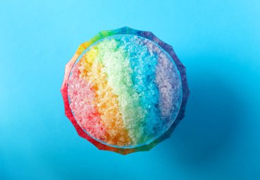 Gökkuşağı, açık mavi arka planda cam tatlı kasesinde buzu traş ediyor.