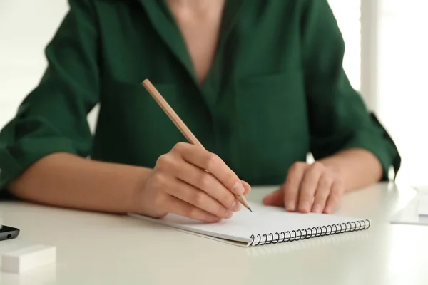 白いテーブルでメモ帳に鉛筆で描く女性 クローズアップ — ストック写真