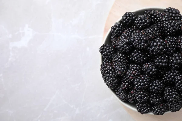 stock image Fresh ripe blackberries in bowl on white table, top view. Space for text