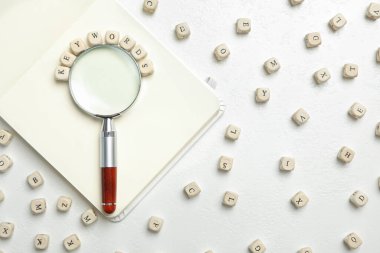 KEYWORDS kelime boncuklar, büyüteç ve beyaz masa üzerinde not defteri, düz yatıyordu