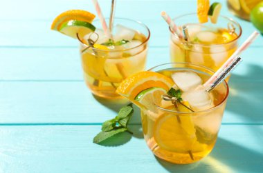 Açık mavi ahşap masada portakal ve limon dilimleri ile nefis ferahlatıcı bir içecek.