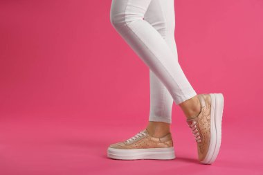 Pembe arka planda ayakkabı giyen kadın, yakın plan. Metin için boşluk