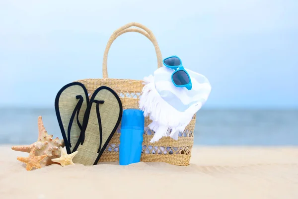Bag and beach objects on sand near sea