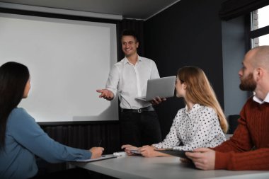 İş adamları konferans odasında video projeksiyon ekranıyla hoparlör dinliyor