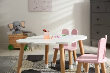 Çocuk odasında küçük masa ve tavşan kulaklı sandalyeler. İç tasarım