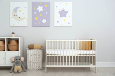 Bebek odasının içinde beşik ve duvarında sevimli posterler var.
