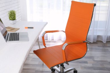 Ofis sandalyesi ve ahşap masası olan rahat bir iş yeri.