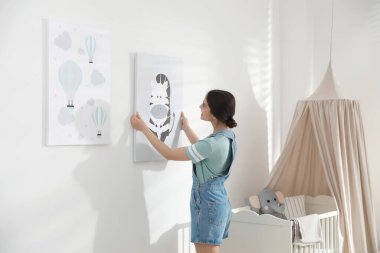 Dekoratör beyaz duvara resim asıyor. Çocuk odası iç tasarımı.