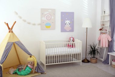 Bebek odasının içinde sevimli posterler, çadır ve rahat bir beşik var.