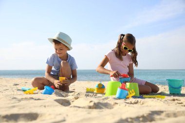 Kumsalda plastik oyuncaklarla oynayan sevimli çocuklar.
